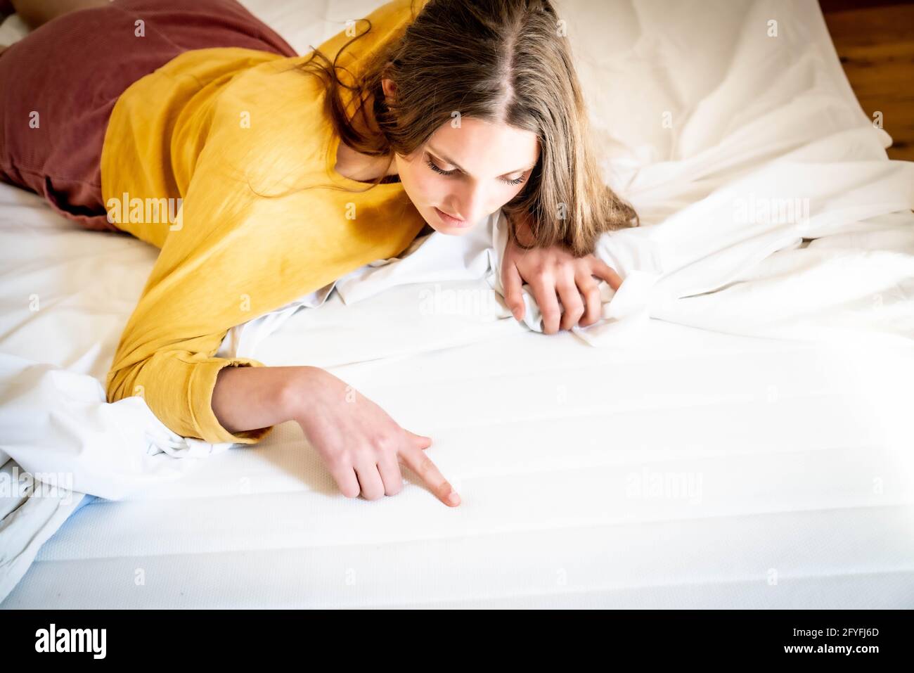 Frau überprüft ihre Matratze. Stockfoto