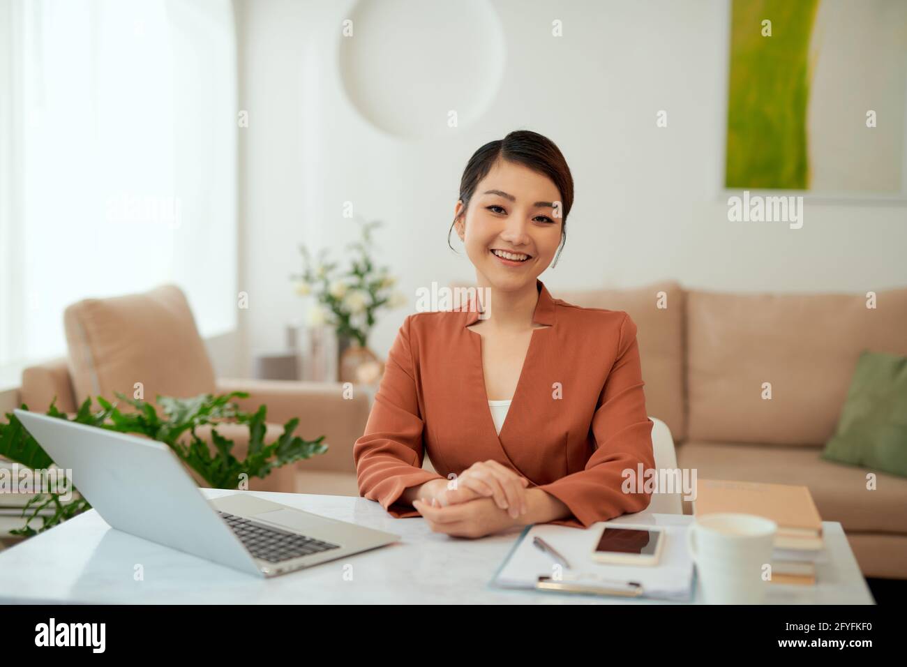Asiatische Frau, die im Heimbüro mit einem Laptop arbeitet. Stockfoto