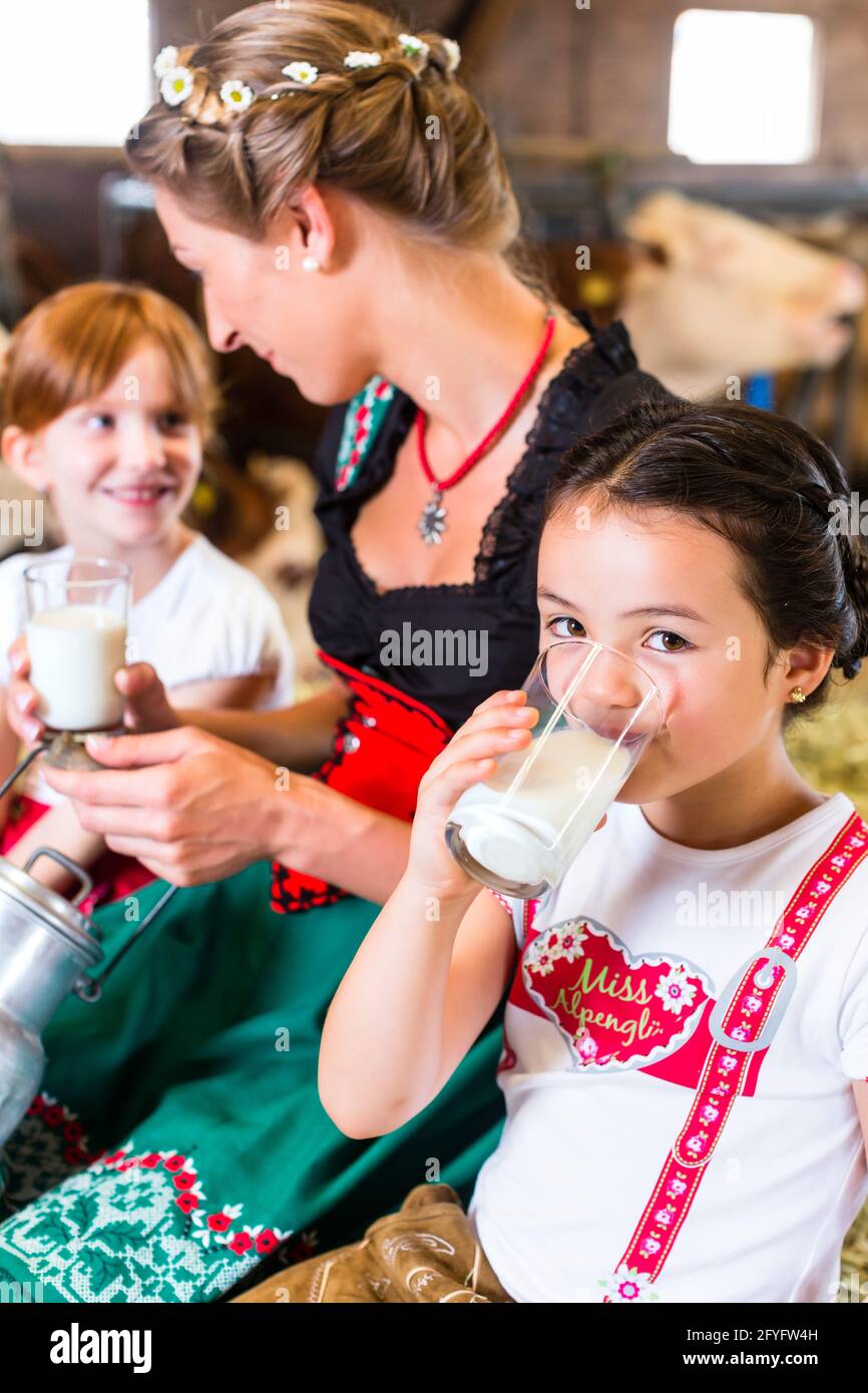 Bayerin sitzen mit Kinder im Kuhstall auf Heuballen trinken frischen Milch Stockfoto