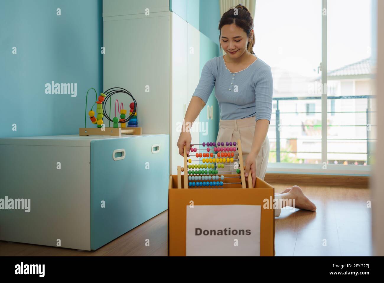 Die asiatische Mutter wählt das Spielzeug ihrer Kinder, das nicht spielt, und legt Spendenboxen an das Spendenzentrum. Stockfoto