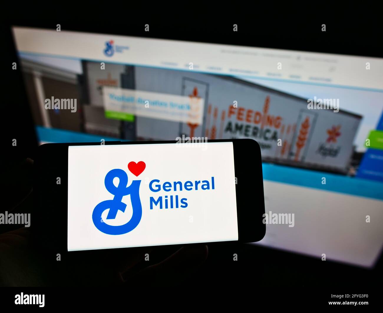 Person, die das Smartphone mit dem Logo des amerikanischen Lebensmittelverarbeitungsunternehmens General Mills Inc. Auf dem Bildschirm vor der Webseite hält. Konzentrieren Sie sich auf die Telefonanzeige. Stockfoto