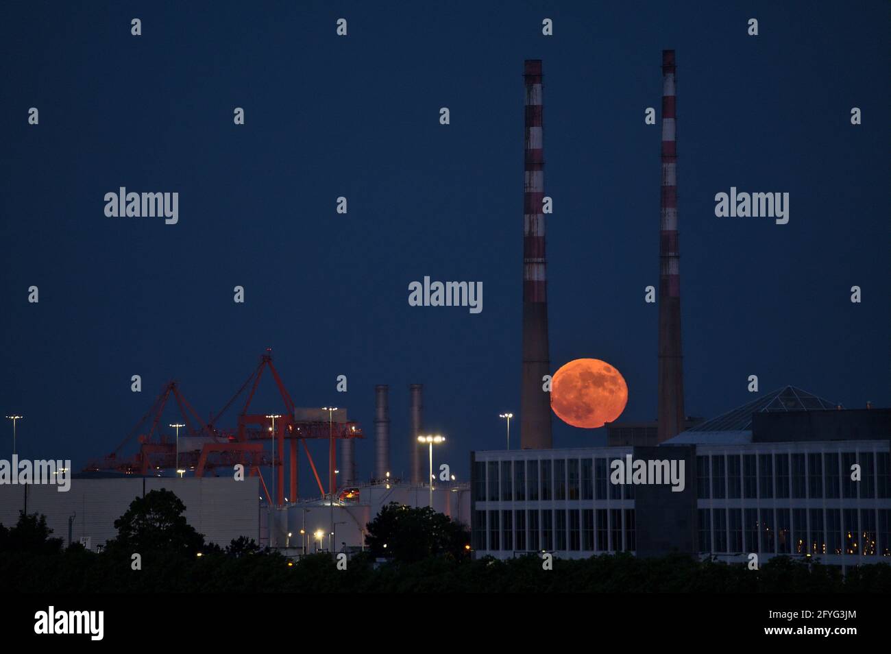 Wunderschöne Aussicht auf rote Superblumen der Mond steigt am irischen Himmel zwischen den berühmten Schornsteinen der Poolbeg Generating Station (Poolbeg CCGT) am 26. Mai 2021 auf f Stockfoto