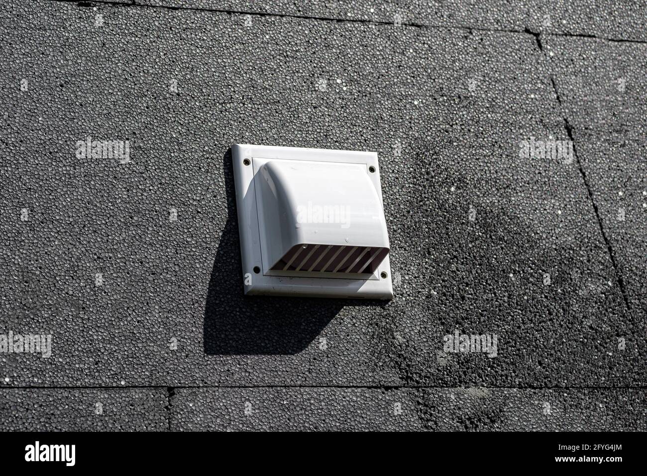 Ein Kunststoff-Lüftungsgitter an der Gebäudefassade aus schwarzem isolierendem Styropor. Stockfoto