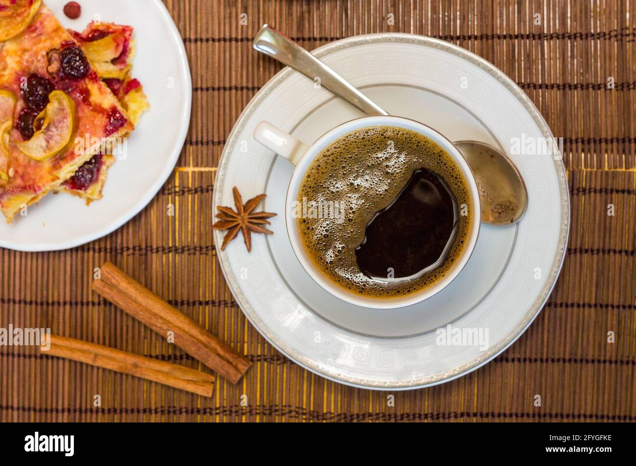 Stillleben - eine Tasse schwarzen Kaffee, hausgemachte Kekse mit Obst auf einer Bambusmatte Stockfoto