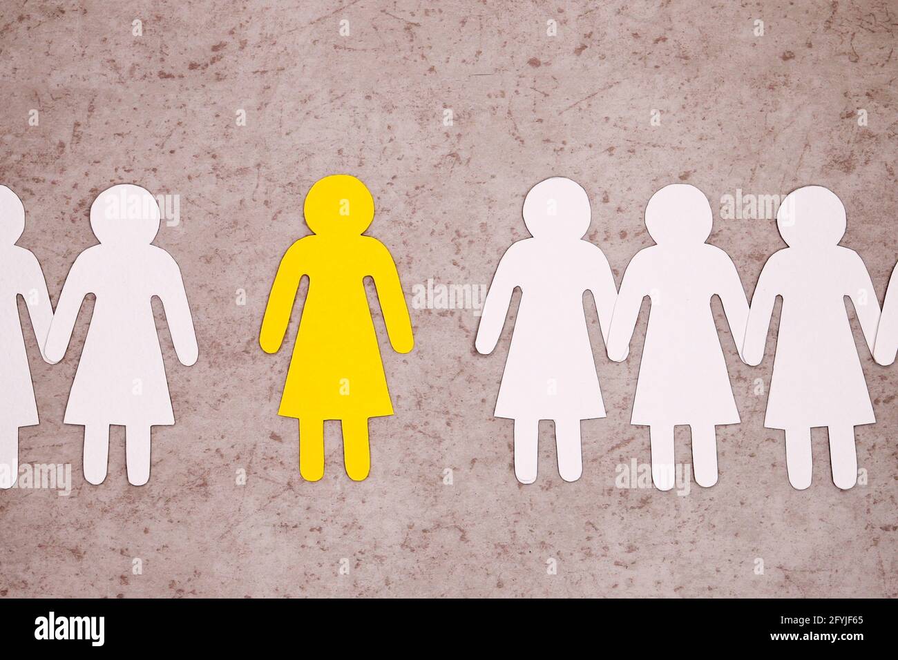 Frauenkollektiv. Weibliche Kollegen nehmen keine Neulinge in die Gesellschaft auf. Einsamkeit und Mobbing. Eine gelbe Figur auf grauem Hintergrund um das Weibchen Stockfoto