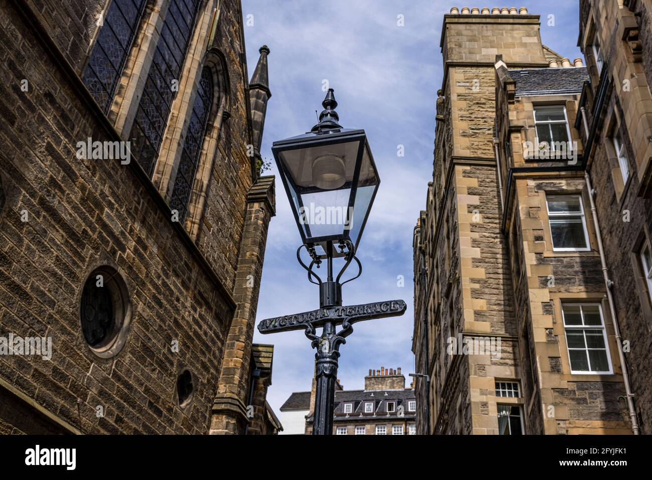 Fotos einer antiken Straßenlampe, die die Inschrift Victoria Terrae trägt. Die Lampe befindet sich zwischen zwei hohen Steingebäuden in Edinburgh. Stockfoto