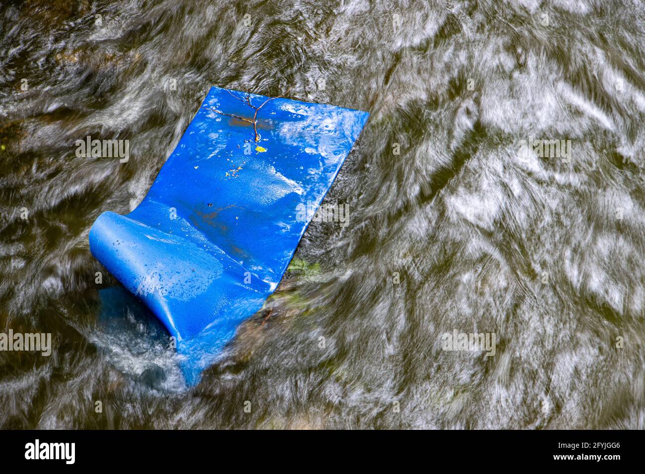 Eine blaue Matte in einem Bach mit schnell fließendem Wasser. Stockfoto