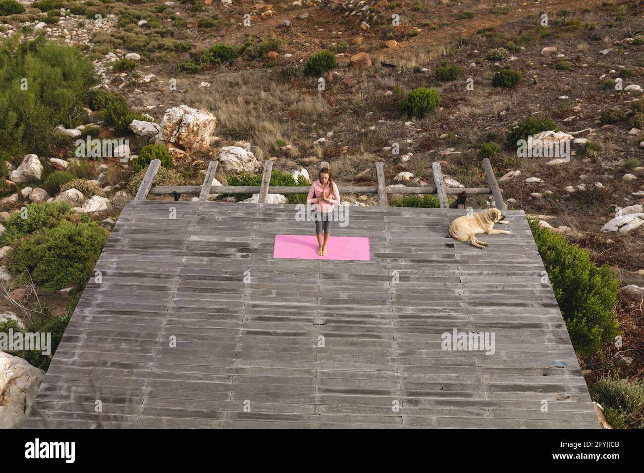 Ruhige kaukasische Frau, die Yoga praktiziert, steht in Meditation an Deck In ländlicher Umgebung Stockfoto