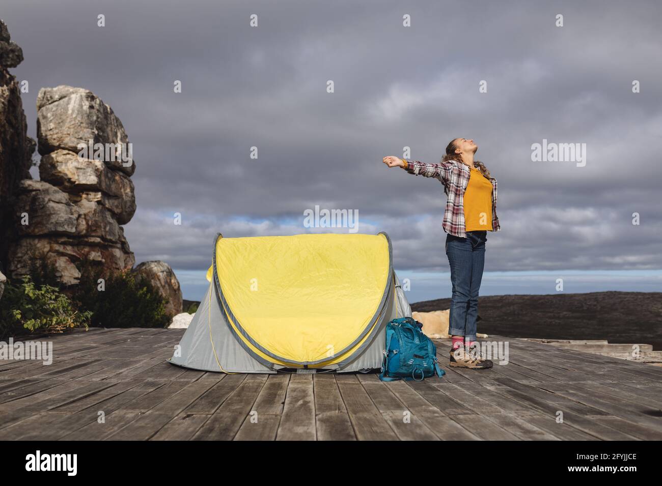 Glückliche kaukasische Frau, die draußen im Zelt auf dem Bergdeck mit ausgestreckten Armen stand Stockfoto