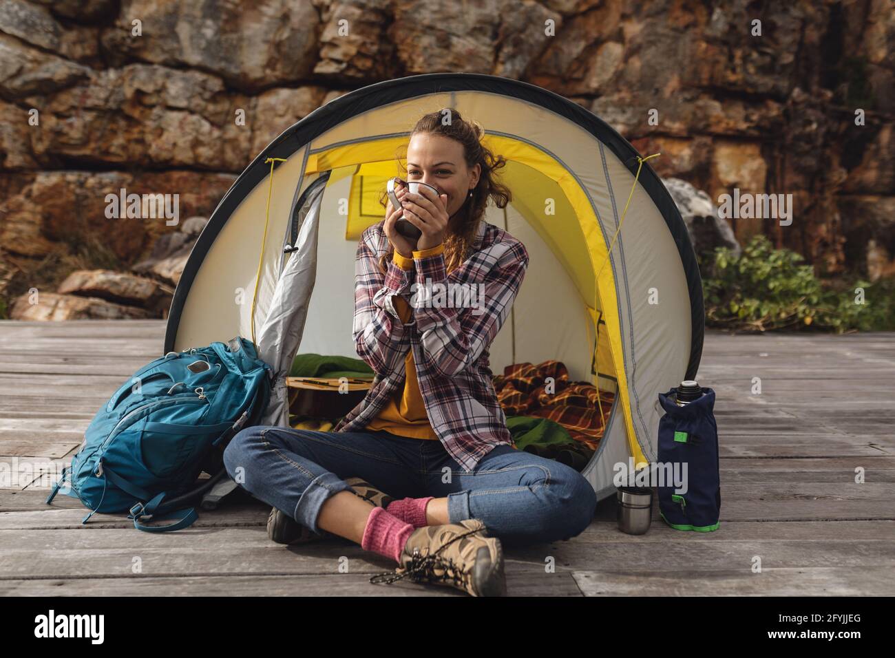 Fröhliche kaukasische Frau, die zelte, beim Kaffee trinkend, draußen im Zelt auf der Bergterrasse saß Stockfoto