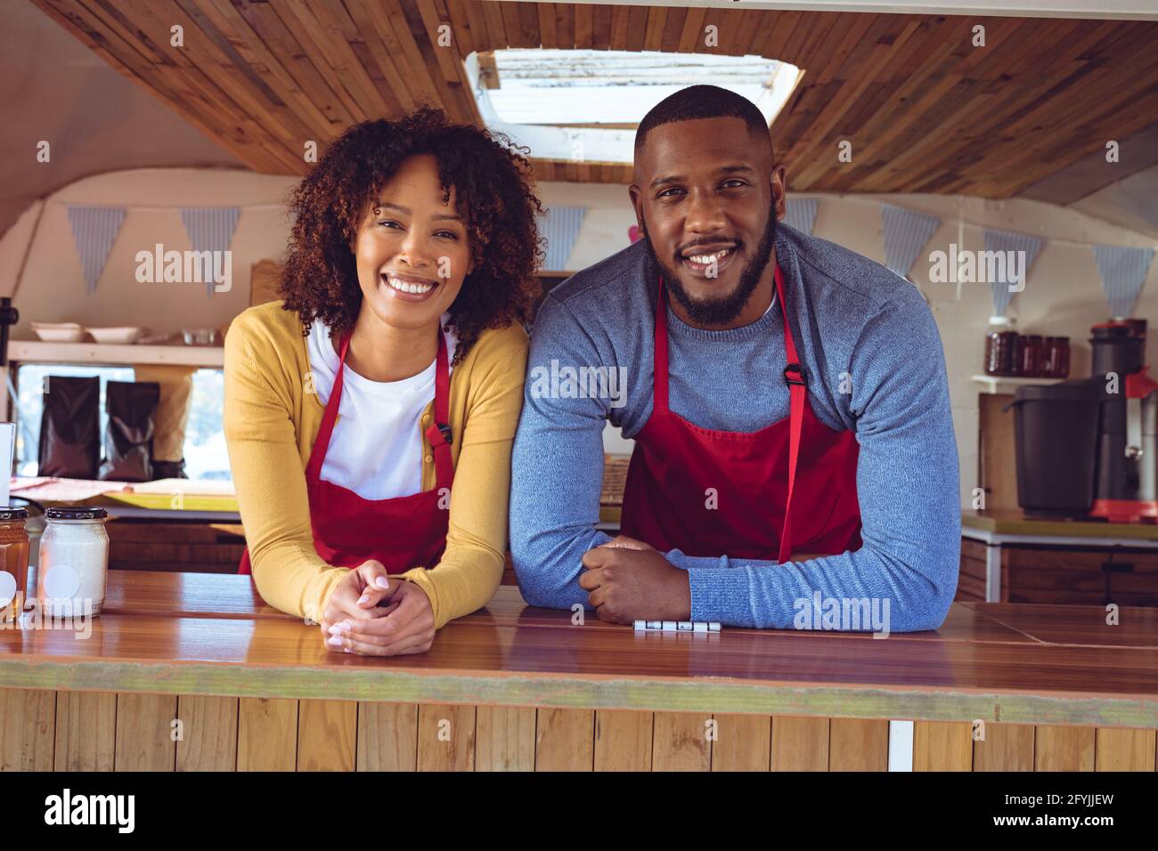 Porträt eines lächelnden, vielfältigen Paares hinter dem Tresen in einem Food Truck Stockfoto