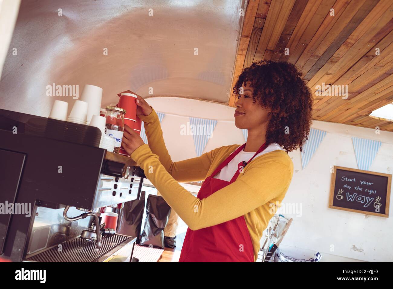 Mixed Race Frau, die Kaffee mit der Kaffeemaschine in Lebensmitteln zubereitet LKW Stockfoto
