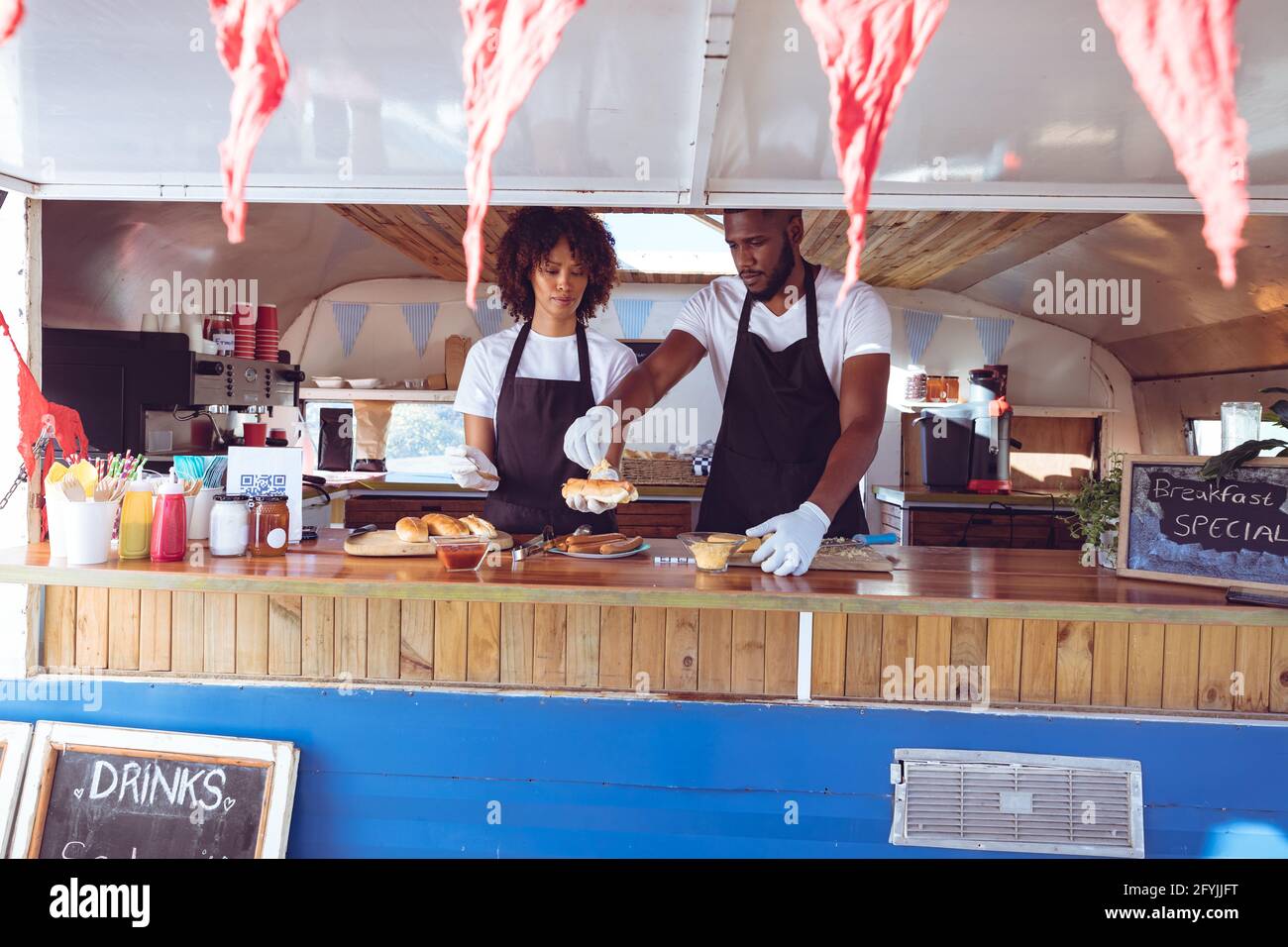 Diverse Paar bereitet Hot Dogs hinter dem Tresen in Food Truck vor Stockfoto