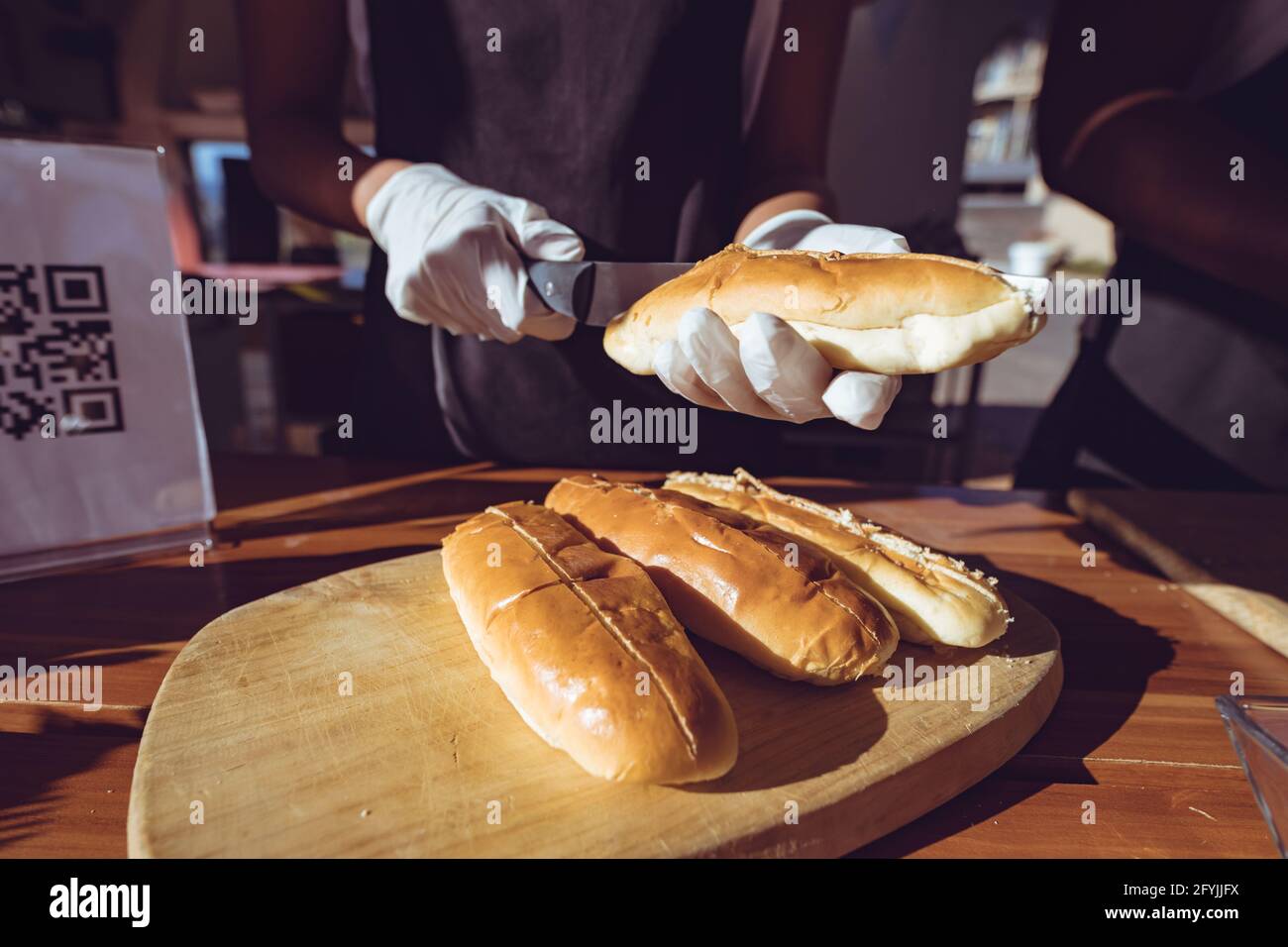 Mittelteil der Frau mit gemischter Rasse, die Hot Dogs hinter dem Tresen vorbereitet Im Food Truck Stockfoto