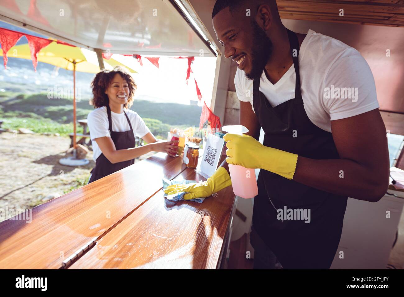 Lächelndes, vielfältiges Paar hinter der Putztheke im Food Truck Stockfoto