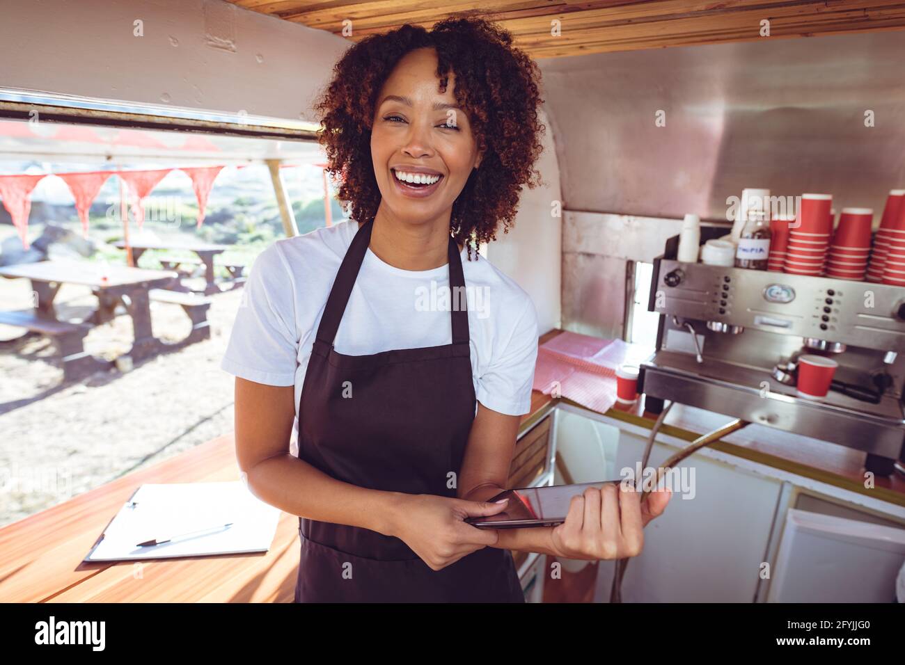 Porträt einer lächelnden Frau mit gemischter Rasse hinter dem Tresen im Smartphone Im Food Truck Stockfoto