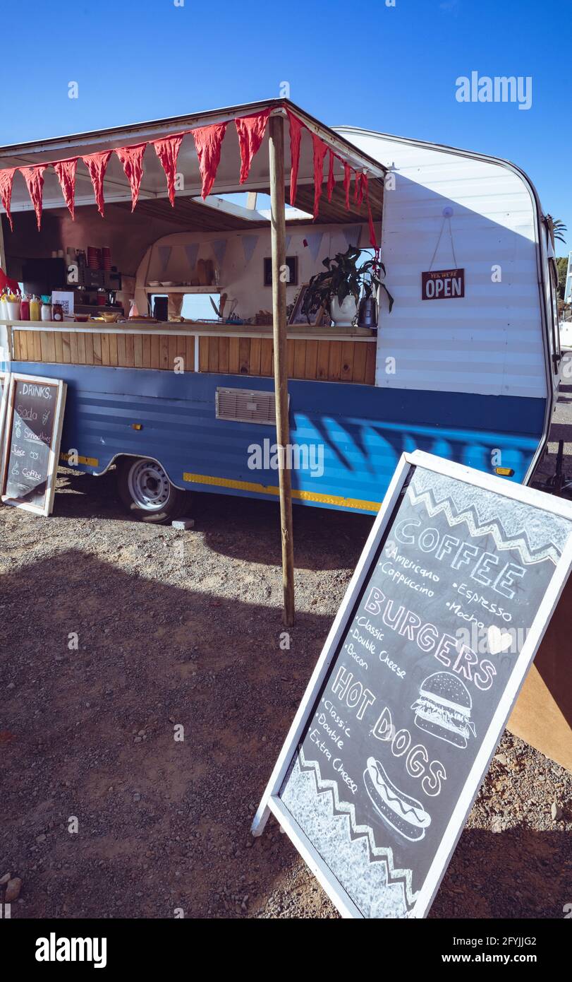 Gesamtansicht des Food Trucks mit roten Verfärbungs- und Speisekarten Gehen Sie gegen den blauen Himmel Stockfoto