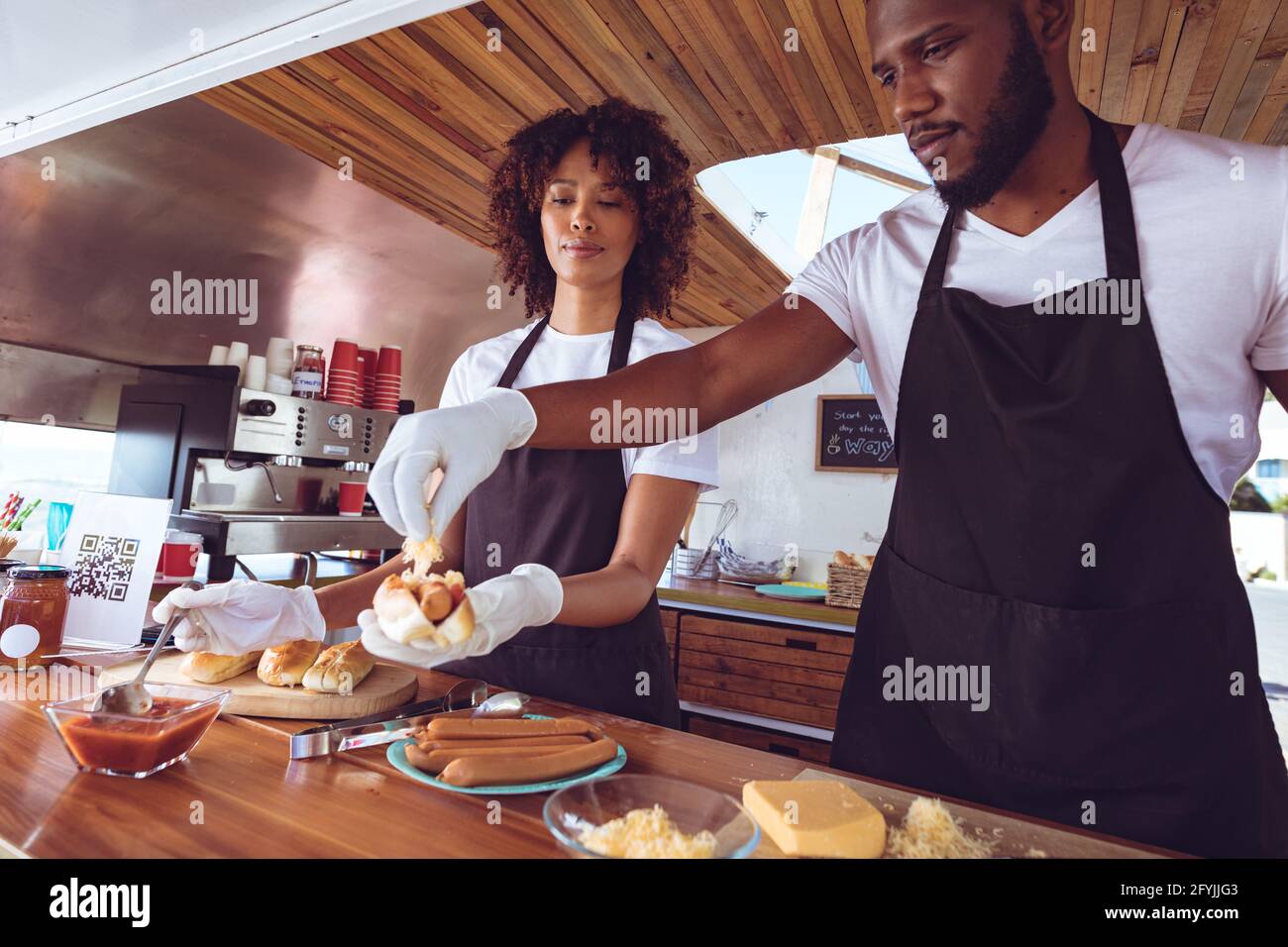Diverse Paar bereitet Hot Dogs hinter dem Tresen in Food Truck vor Stockfoto