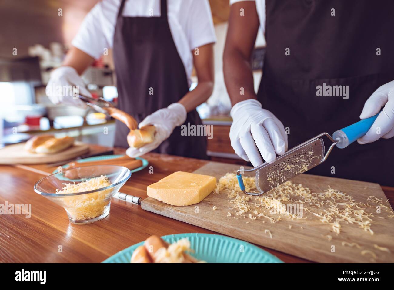 Mittelteil der Mischrasse Frau Reibe Käse hinter Zähler in Foodtruck Stockfoto
