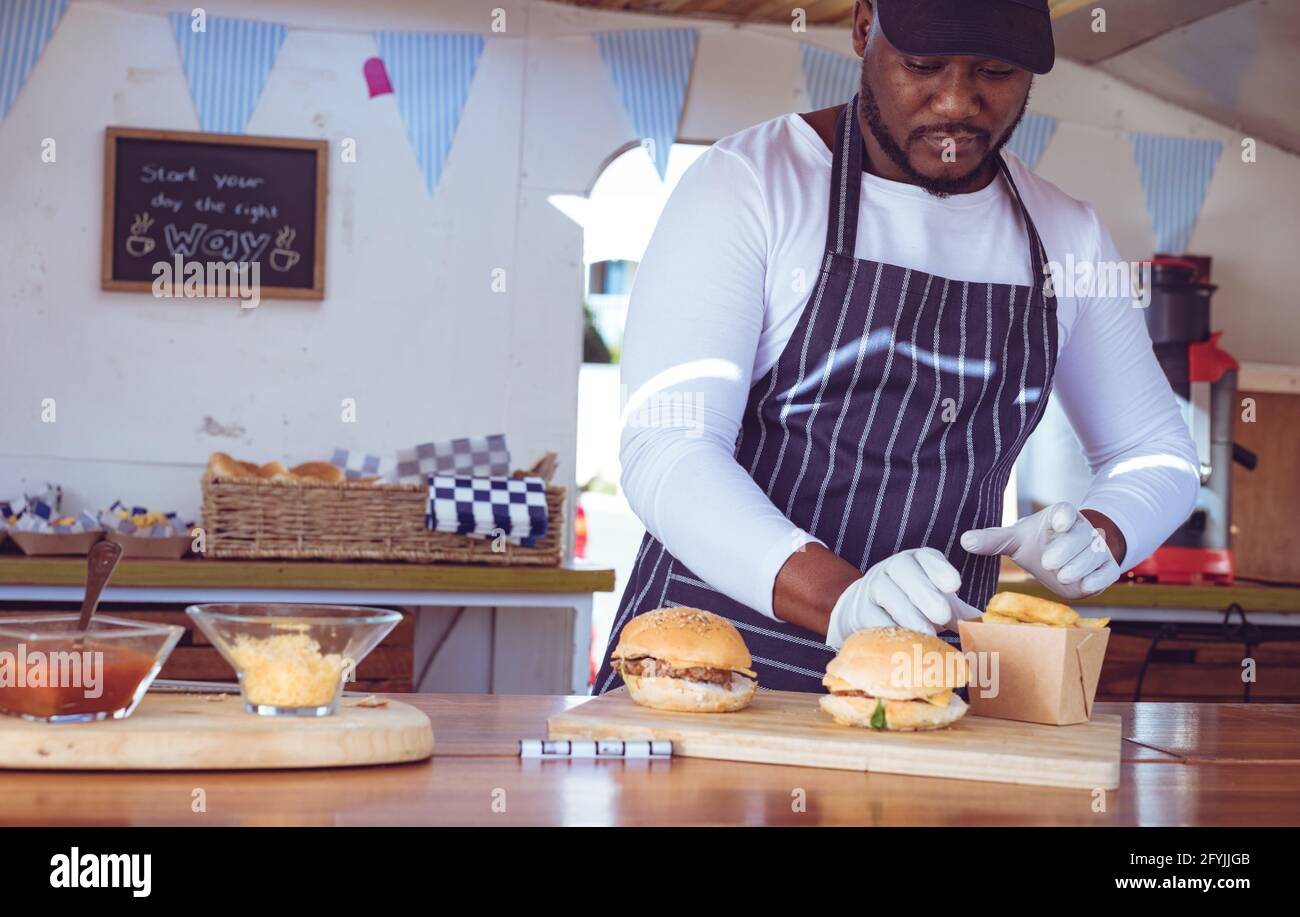 Afroamerikanischer Mann im Food Truck, der Ordnung mit Hamburgern vorbereitet Auf der Arbeitsplatte Stockfoto