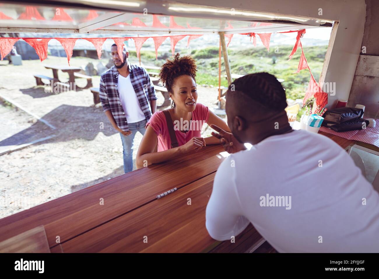 Afroamerikanischer Mann in einem Food Truck, der von einer Frau bestellt wurde Kunde Stockfoto
