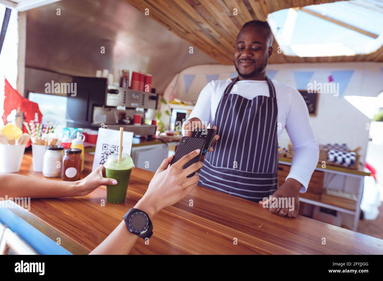 Afroamerikanischer Mann in Lebensmittel-LKW unter Smartphone-Zahlung Holding Terminal Stockfoto