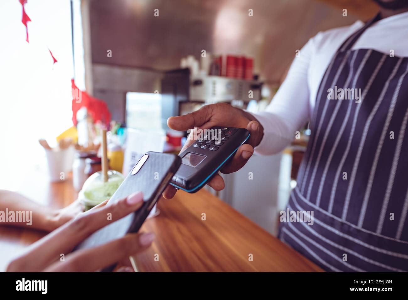 Mittelteil des afroamerikanischen Mannes in Food Truck mit Smartphone Zahlungsterminal Stockfoto