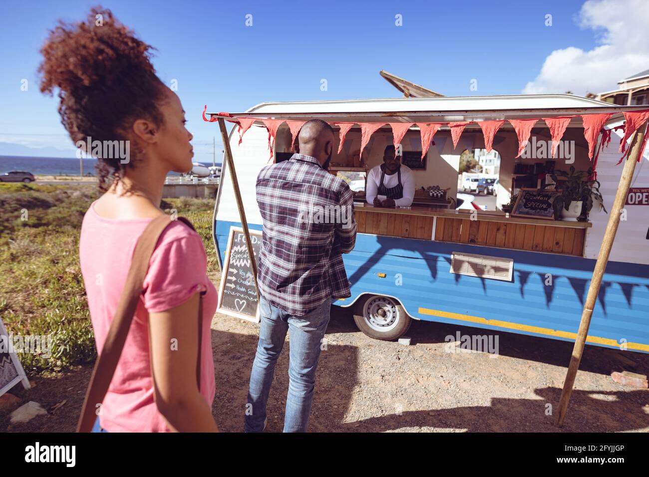 Lächelnder afroamerikanischer Mann in einem Food Truck, der die Bestellung von abnimmt Männlicher Kunde Stockfoto