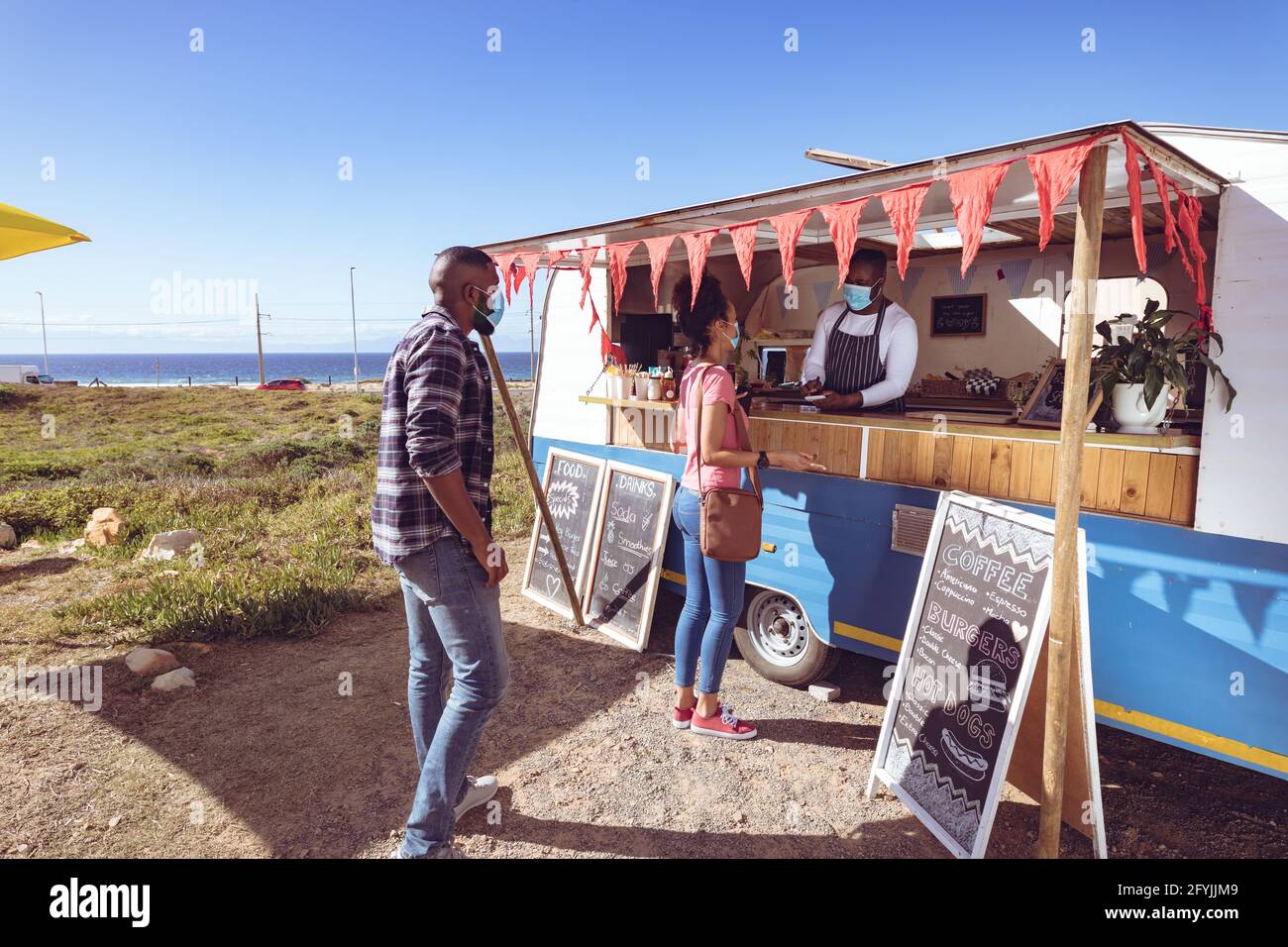 afroamerikanischer Mann mit Gesichtsmaske bei der Einnahme von Food-Trucks Bestellung von weiblicher Kundin Stockfoto
