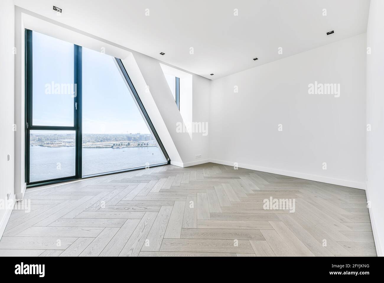 Unmöblierte Zimmereinrichtung mit Parkettboden und weißen Wänden und Wandfenster in Luxusapartment Stockfoto