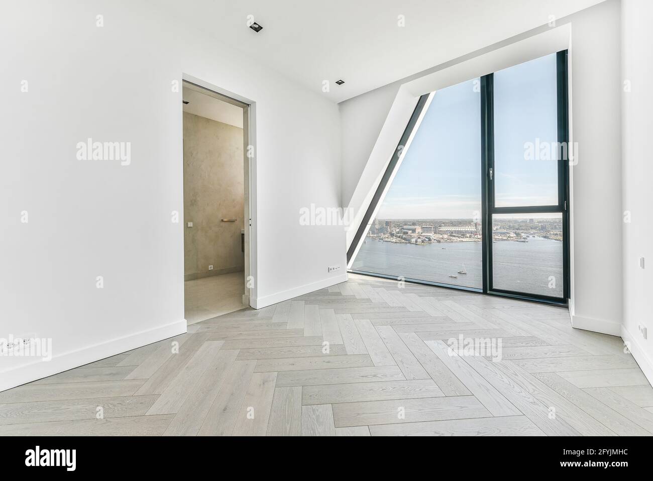 Unmöblierte Zimmereinrichtung mit Parkettboden und weißen Wänden und Wandfenster in Luxusapartment Stockfoto