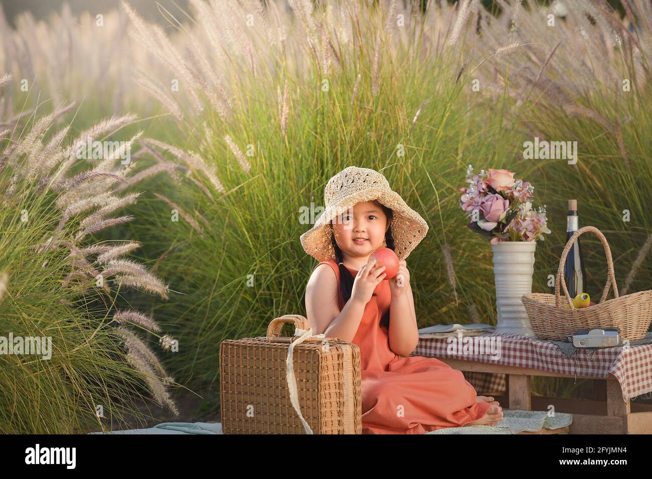 Lächelndes Mädchen, das einen Apfel hält, während es ein Picknick macht, Thailand Stockfoto