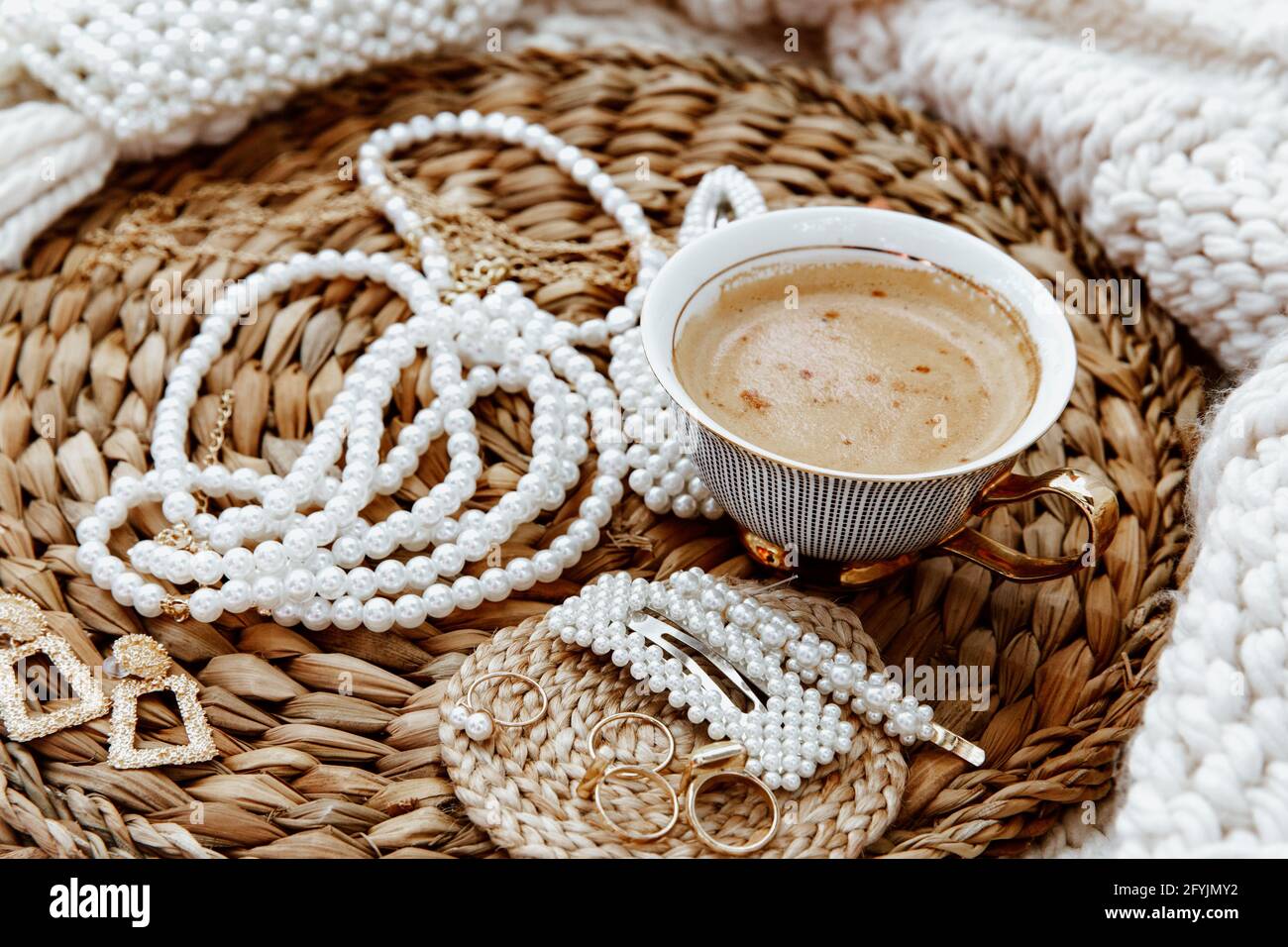 Tasse Kaffee mit Ringen, Ohrringen, Halsketten und Haarclips Stockfoto