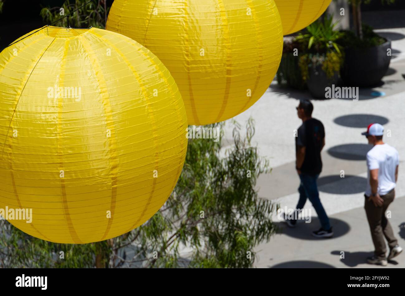 Im Einkaufszentrum Santa Monica Place in Santa Monica, Kalifornien, USA, laufen die Käufer unter gelben Papierlaternen, die den „Pride Month“ feiern Stockfoto