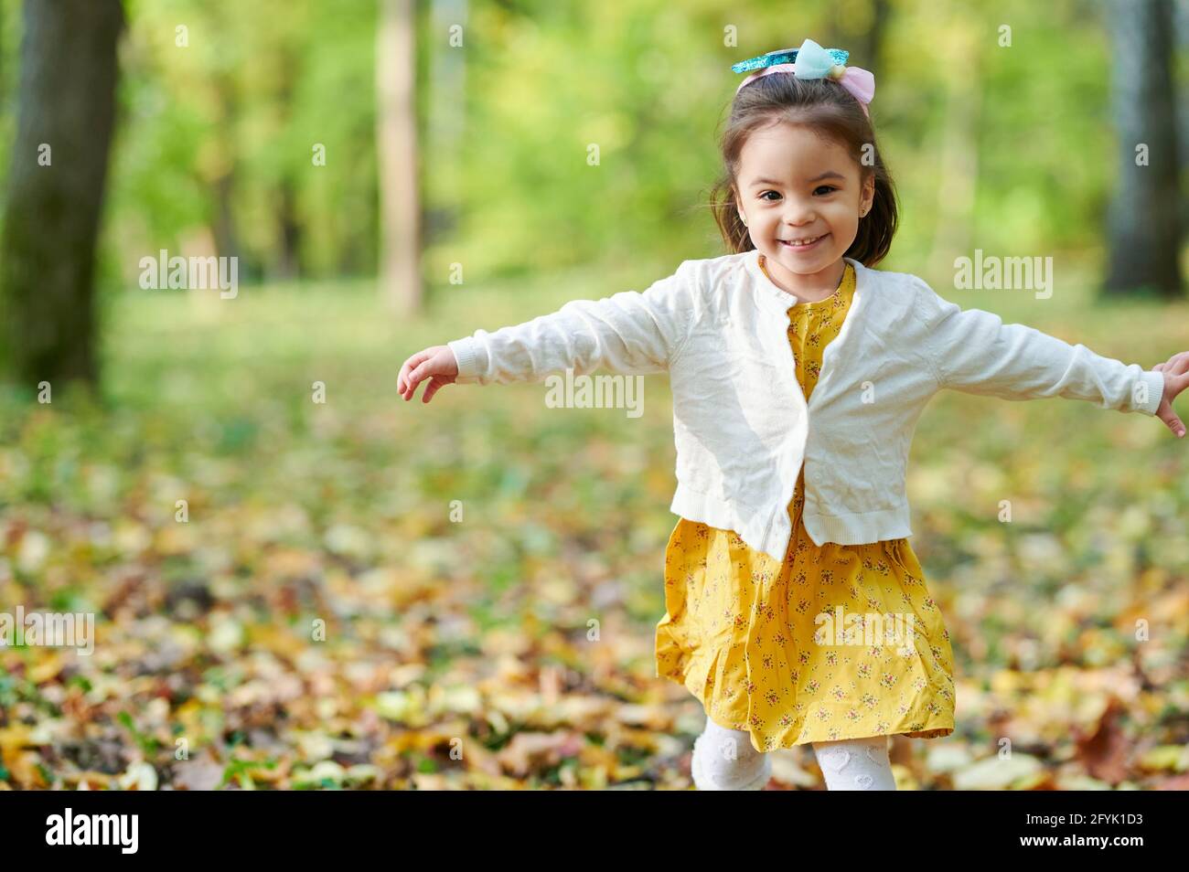 Kinderlauf mit offenen Händen auf verschwommenem Parkhintergrund Stockfoto
