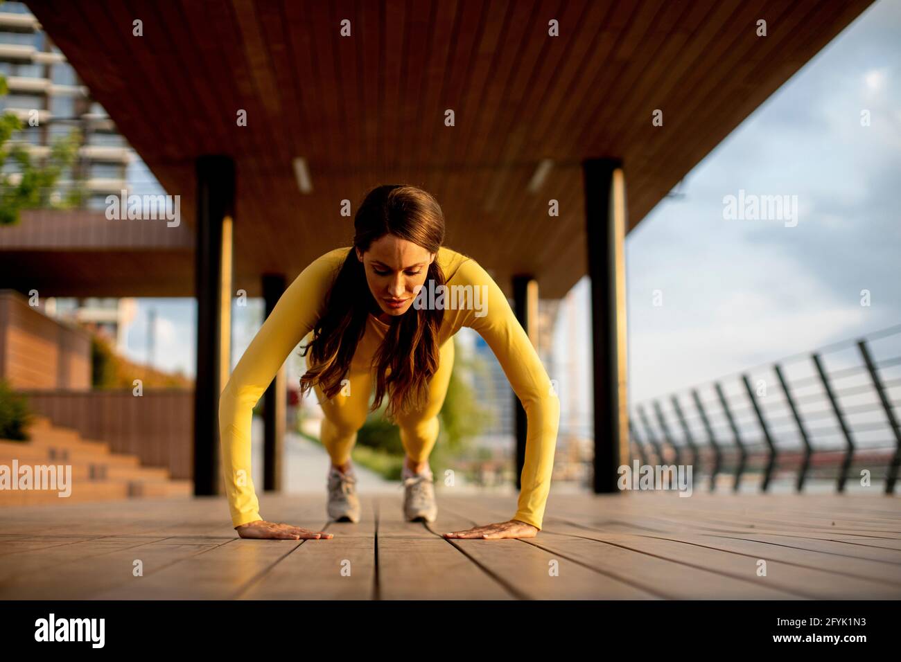 Hübsche junge Frau, die Liegestütze auf einem Holzsteg bei der aufführt Fluss Stockfoto