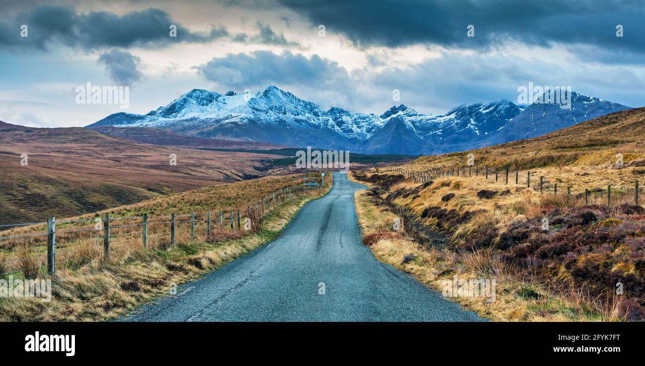 Die Straße hinunter in Richtung der schneebedeckten Cuillin Berge auf der Isle of Skye. Stockfoto