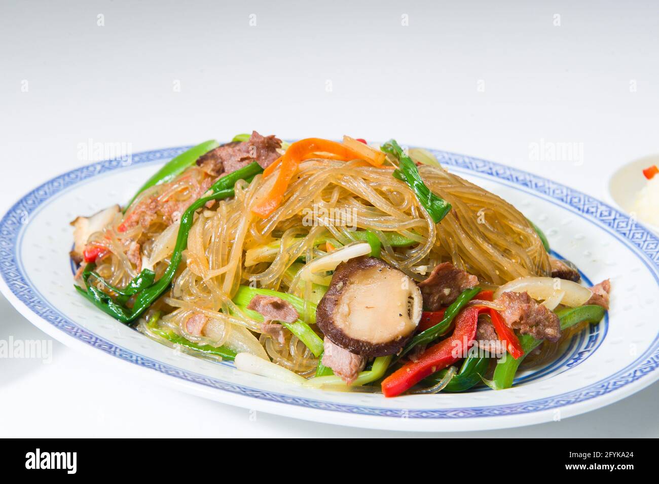 Asiatische Nudeln mit Rindfleisch und Pilzen in einem koreanischen Restaurant. Weißer Hintergrund. Stockfoto