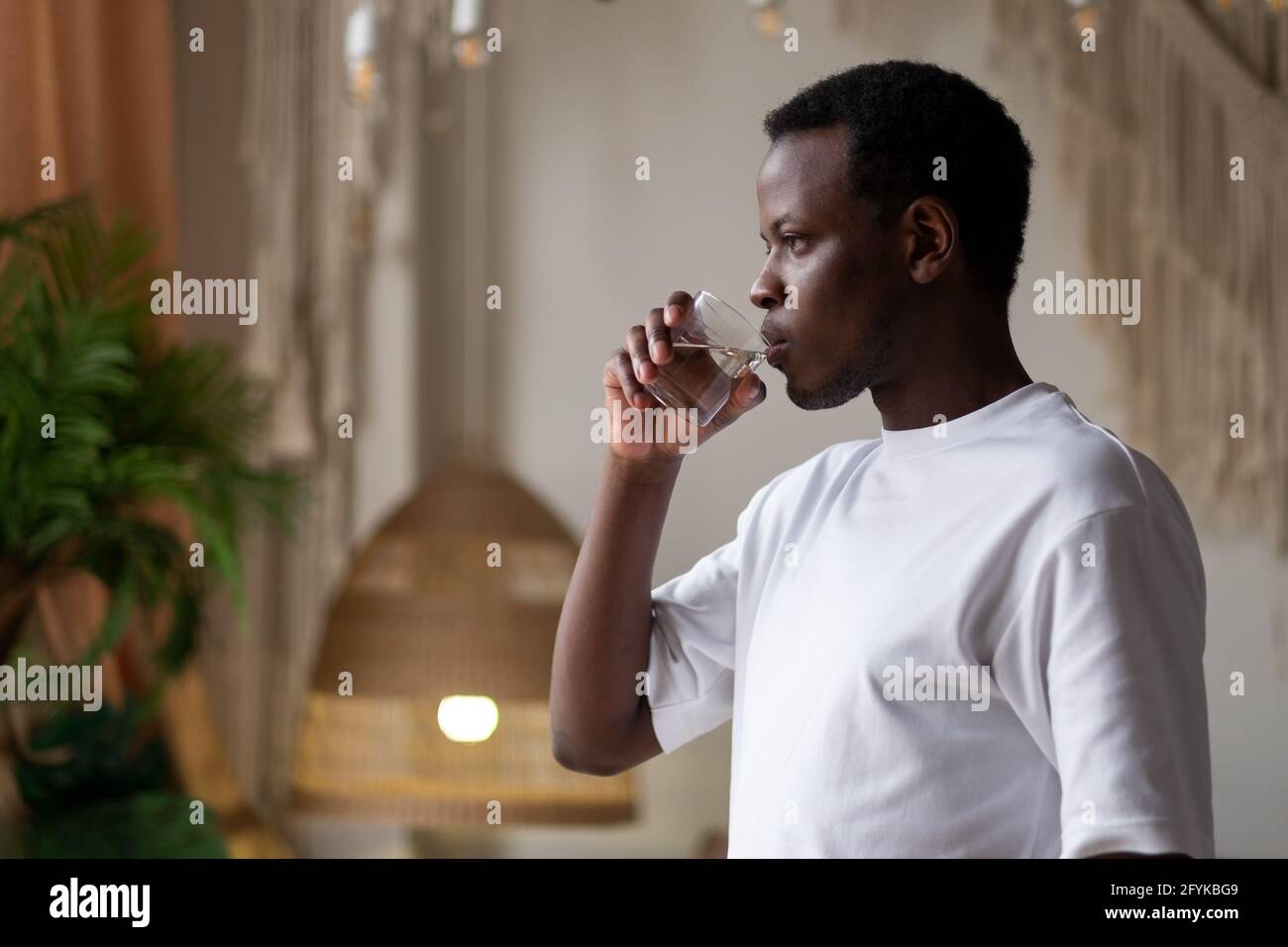 Afrikanischer Athlet zu Hause mit einem Glas Wasser nach dem Sporttraining. Stockfoto