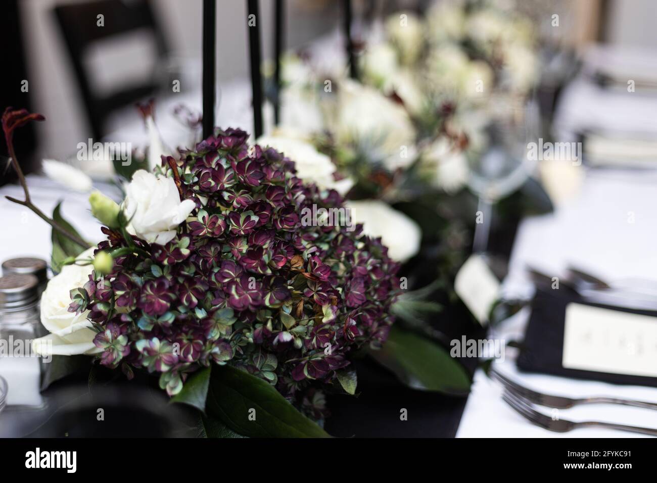 Wunderschöne weiße Rosen mit grünen und violetten Akzenten in einem Formelles Abendessen im Mittelpunkt Stockfoto