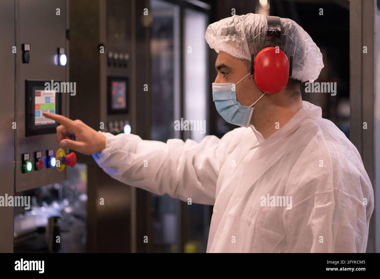 CAPUA, ITALIEN - 23. Mai 2021: Angestellter Arbeiter Mann in maskiertem und schützendem Gewand Bedienpanel der Maschine und Kontrollen. Capua, Italien, Mai Stockfoto