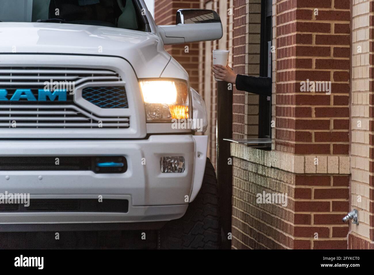 Ein Angestellter, der einem Kunden in einem großen Pickup-Truck am Drive-Thru-Fenster ein Getränk übergibt. (USA) Stockfoto
