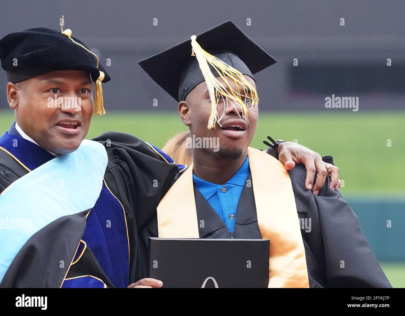 St. Louis, Usa. Mai 2021. Ein Abituriant der Sumner High School versucht, seine Quaste auf seinem Gesicht als Prinzip durchzusehen Dr. Michael Tripplet steht in der Nähe für ein Foto während der Anfangszeremonien für sechs St. Louis High Schools im Busch Stadium in St. Louis am Freitag, den 28. Mai 2021. Über 600 Senioren nahmen an den Abschlussfeiern Teil. Foto von Bill Greenblatt/UPI Credit: UPI/Alamy Live News Stockfoto