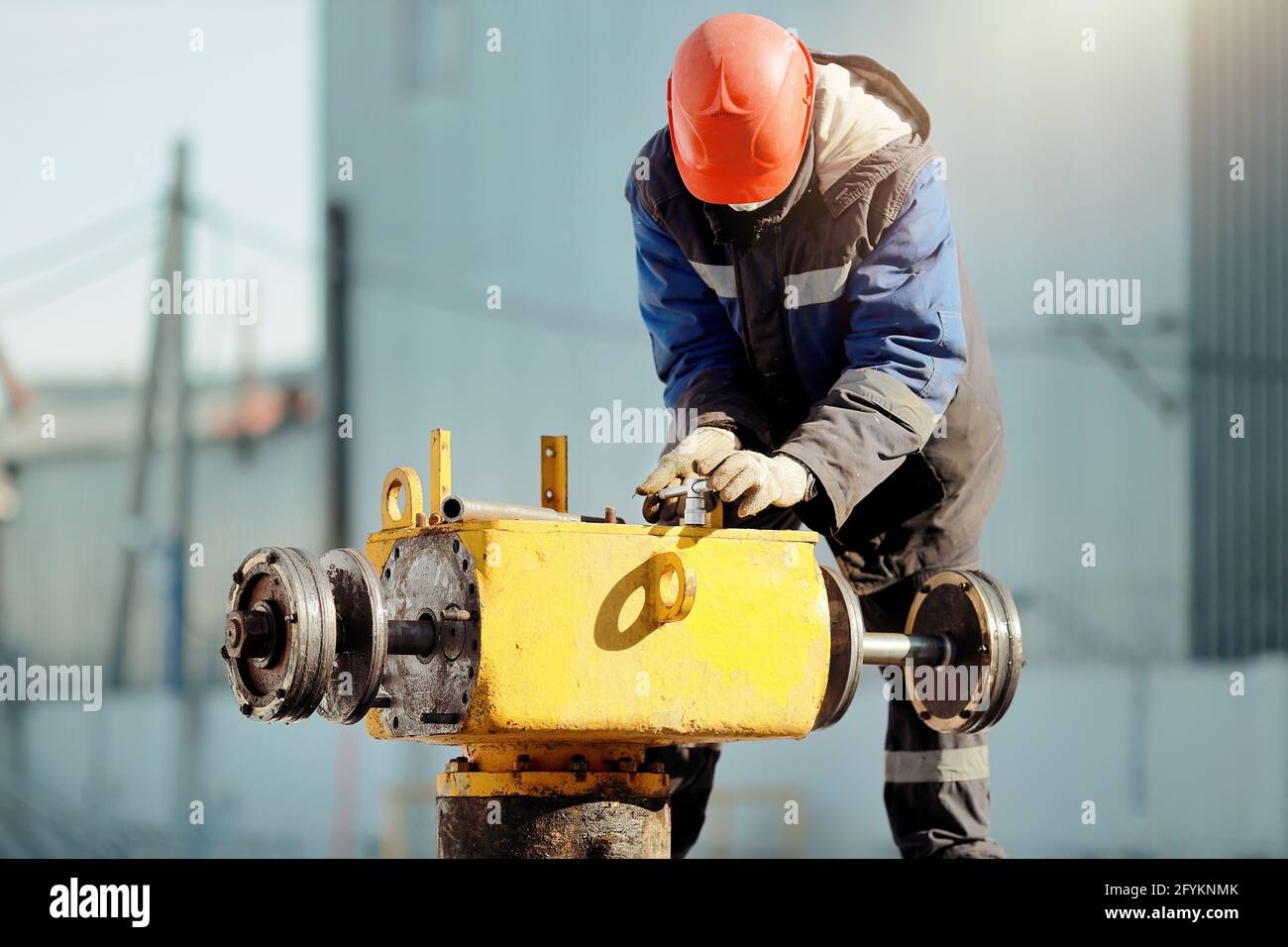 Ein Mann in Arbeitskleidung und einem Hut arbeitet im Winter mit Gasgeräten im Freien. Reparatur des Linearkrans der Hauptgasleitung. Stockfoto