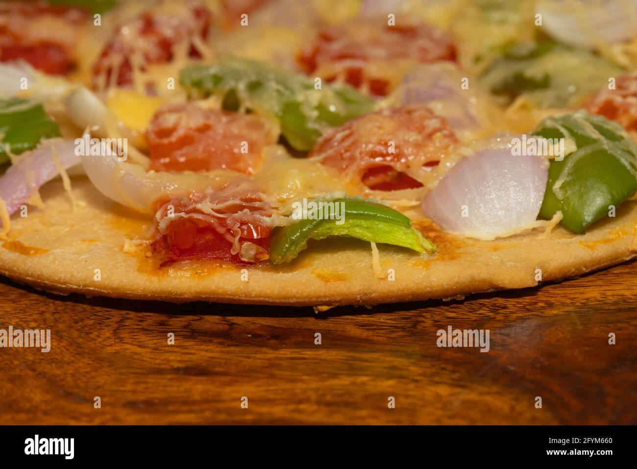 Seitenansicht von frisch gebackener und geschnittener Pizza mit den Zutaten, die auf dem Tisch serviert werden Stockfoto