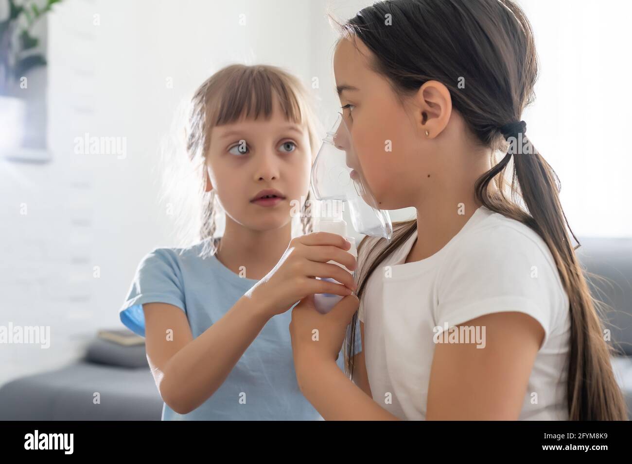 Neun Jahre altes Kind mit allergischem Asthma, das ihre Medikamente durch Abstandshalter inhalierte, während es mit ihren müden Augen ansah Stockfoto