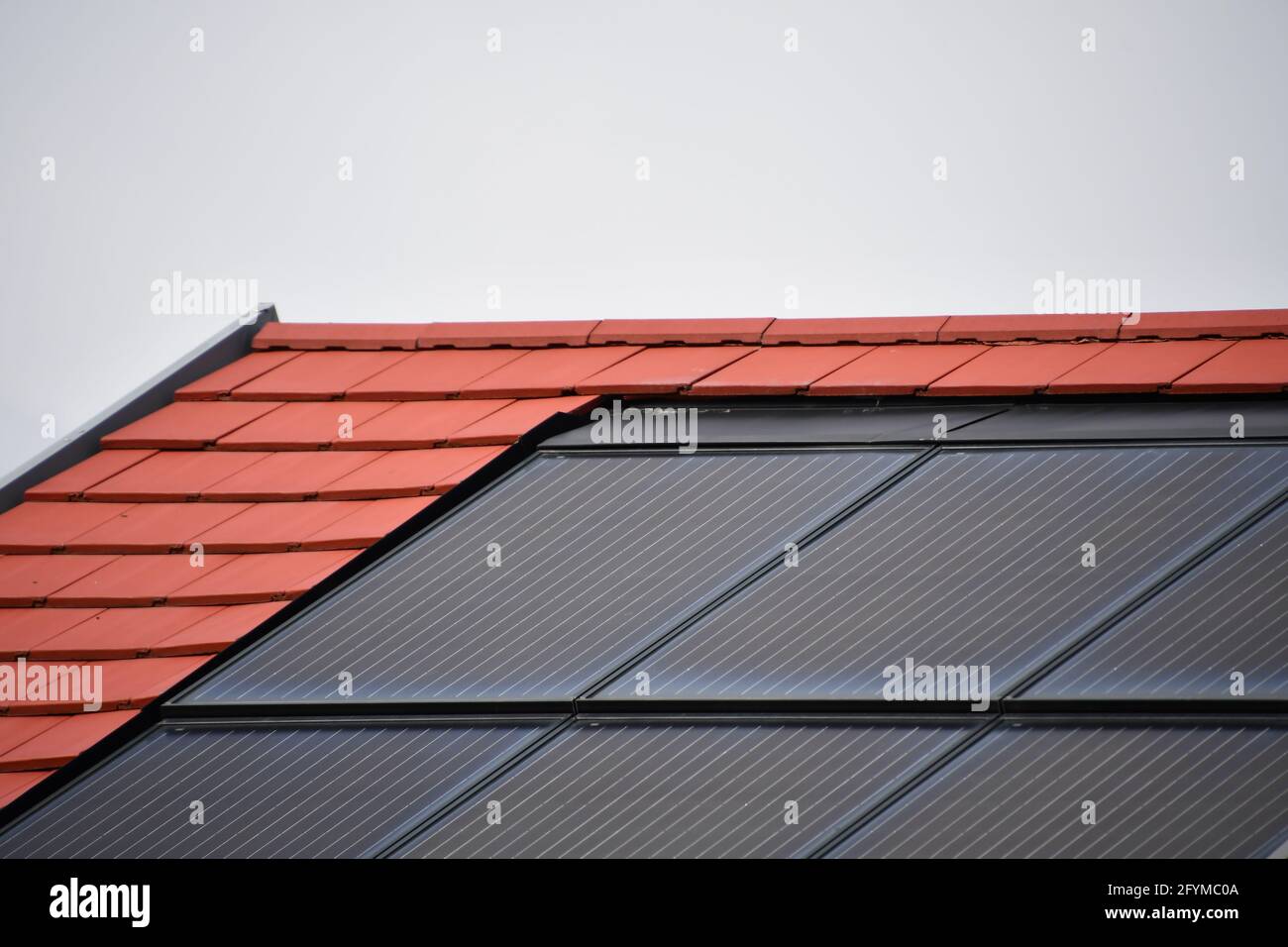 Solarmodule zur Stromerzeugung aus Sonnenlicht, integriert in das Dach eines Einfamilienhauses vor dem Himmel Stockfoto