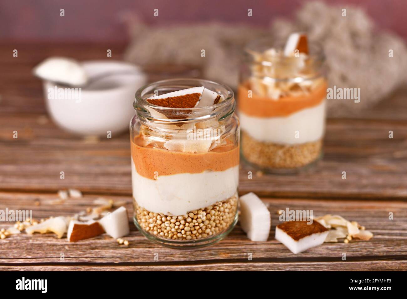 Frühstück oder Dessert in mehreren Schichten mit gepufften Quinoa-Körnern, Joghurt und Kokosflocken und Glasstücken Stockfoto