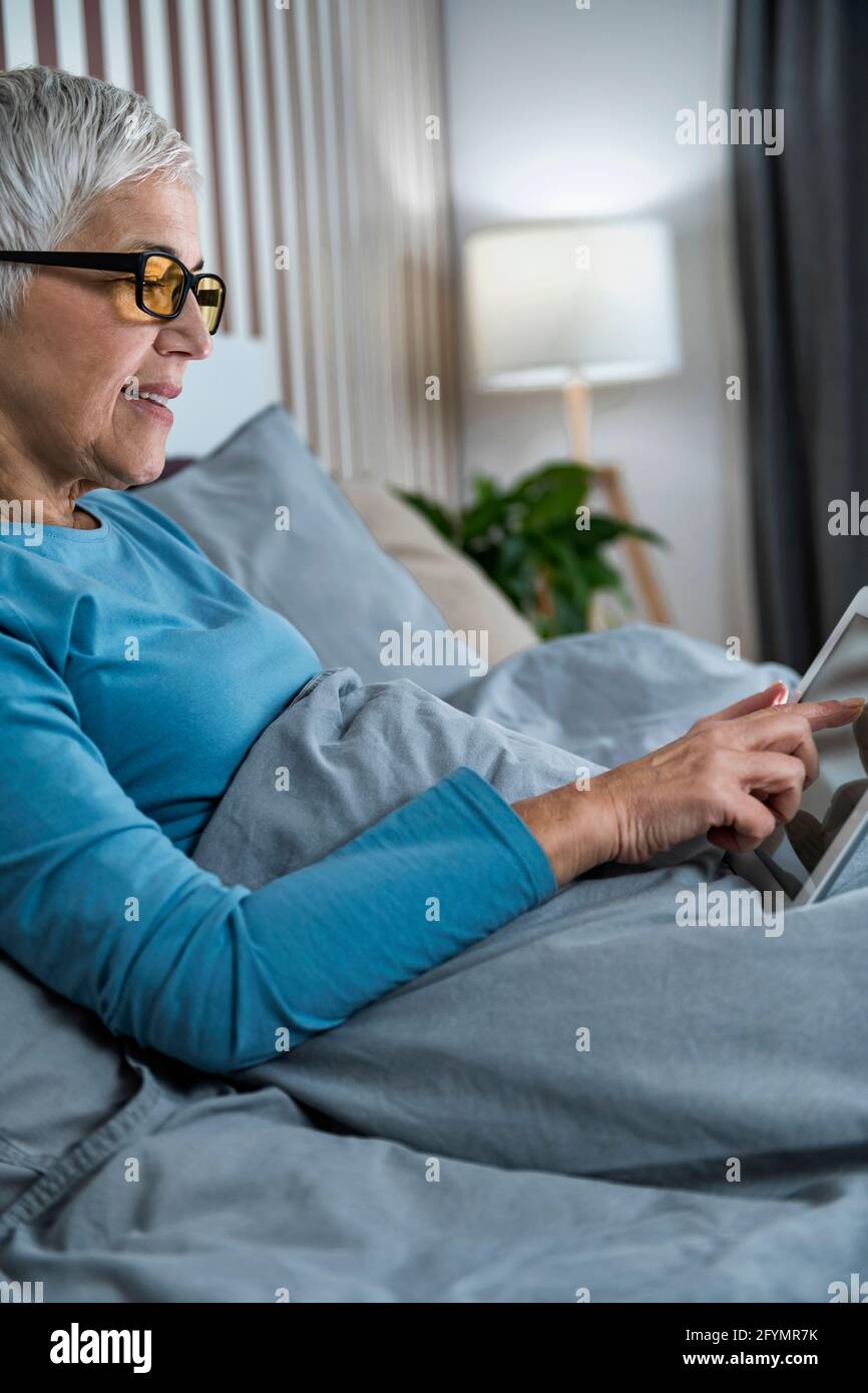Reife Frau trägt eine blaue, lichtblockierende Brille Stockfoto