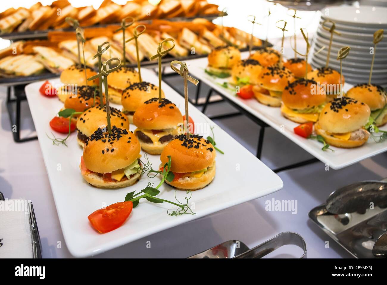 Burger mit Gurke und Käse, Brötchen mit schwarzen Sesamsamen auf dem Food Court. Stockfoto